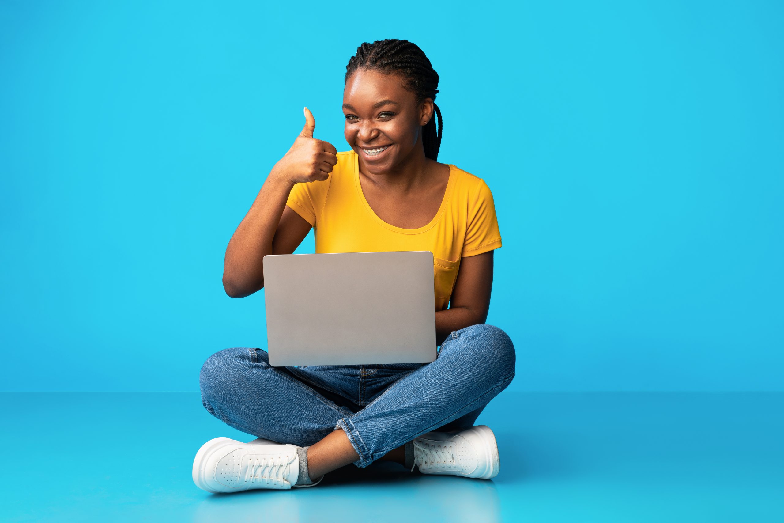 Black Girl Using Laptop Gesturing Thumbs-Up Sitting Over Blue Background